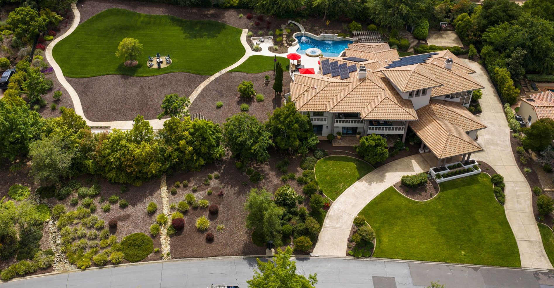 Vista del Prato from above: the lawn and firepit, the pool with its slide, the residence and the circular drive