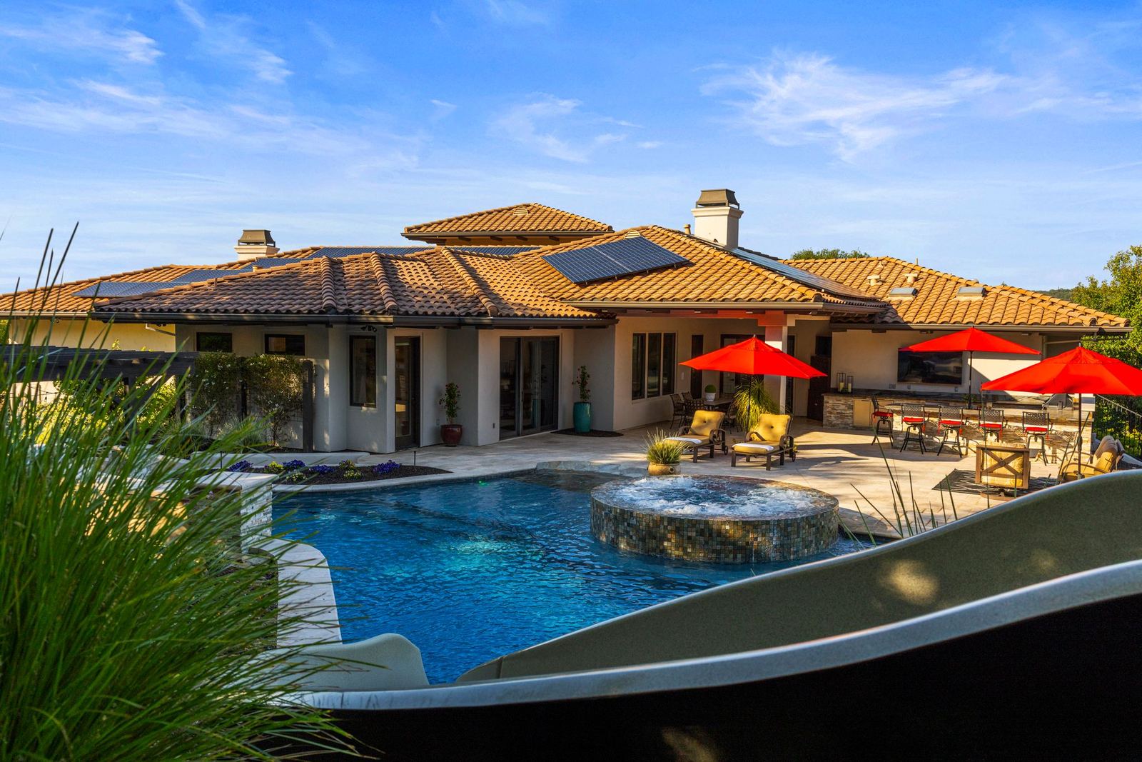 Free-form pool with raised spa, stacked-stone waterfall and slide