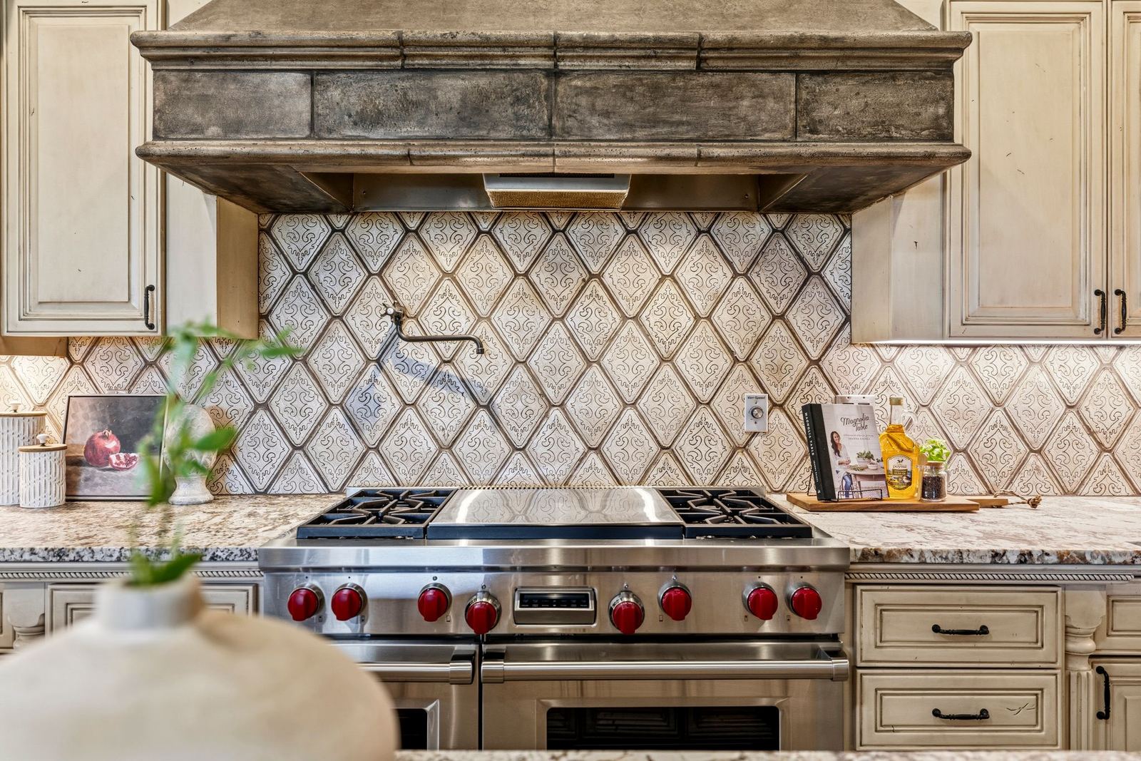 Wolf cooktop with griddle below a custom hood and tile backsplash